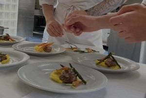 Chef che preparano piatti con carne, purè e verdure in cucina