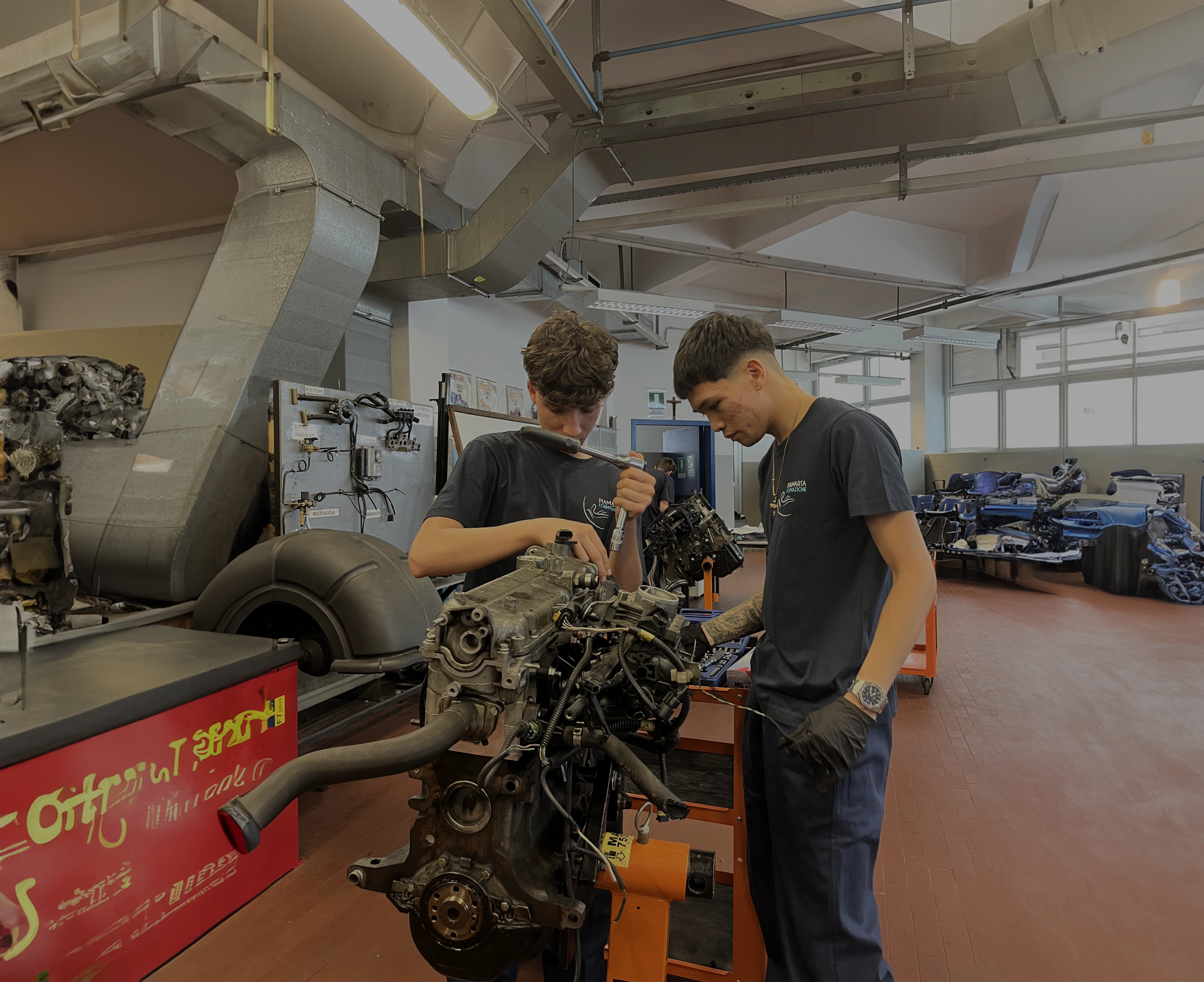 Due giovani meccanici lavorano insieme su un motore in un'officina meccanica.
