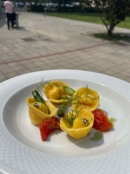 Piatto di tortellini gourmet con pomodori e decorazioni di verdure