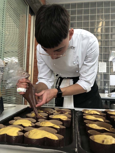 Pasticcere che decora dolci con una sacca da pasticciere in cucina