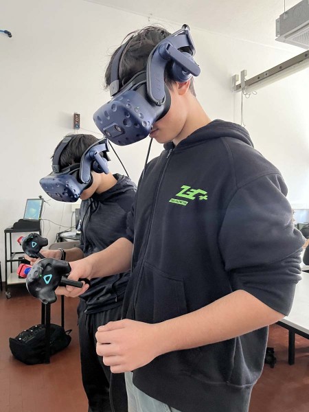 Due studenti indossano visori per realtà virtuale e tengono controller nelle mani durante una sessione di simulazione in aula.