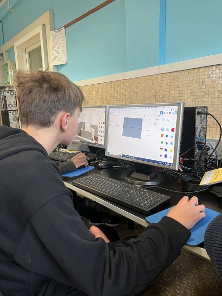 Studente al computer utilizza un software di progettazione grafica in un'aula informatica.