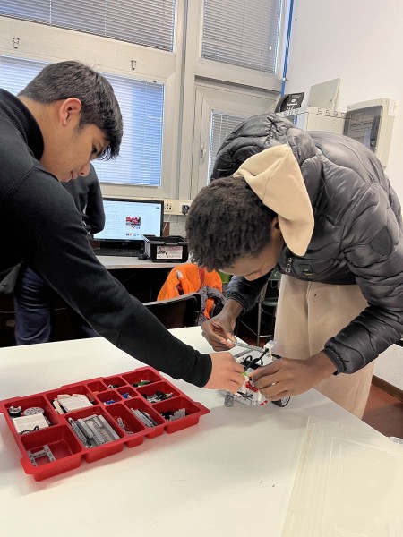 Due studenti lavorano insieme alla costruzione di un robot utilizzando un kit di LEGO Mindstorms in un'aula scolastica.