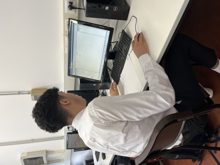 Studente al computer mentre lavora su un progetto tecnico in un'aula informatica.