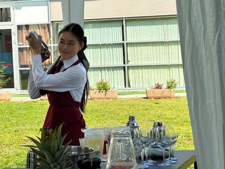 Studentessa con grembiule rosso che agita uno shaker durante una dimostrazione all'aperto