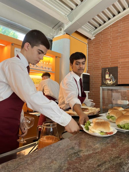 Camerieri in grembiule rosso preparano panini dietro il bancone